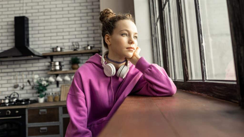 Young woman looking out the window and looking sad