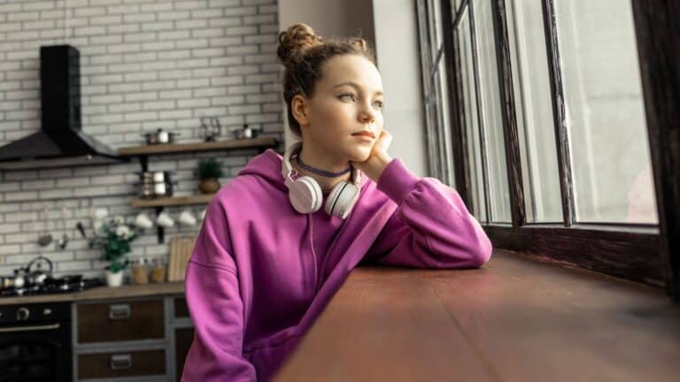Young woman looking out the window and looking sad