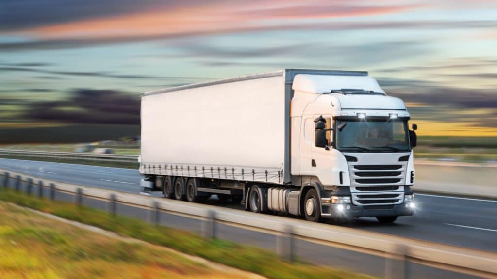 White tractor trailer driving on an empty highway