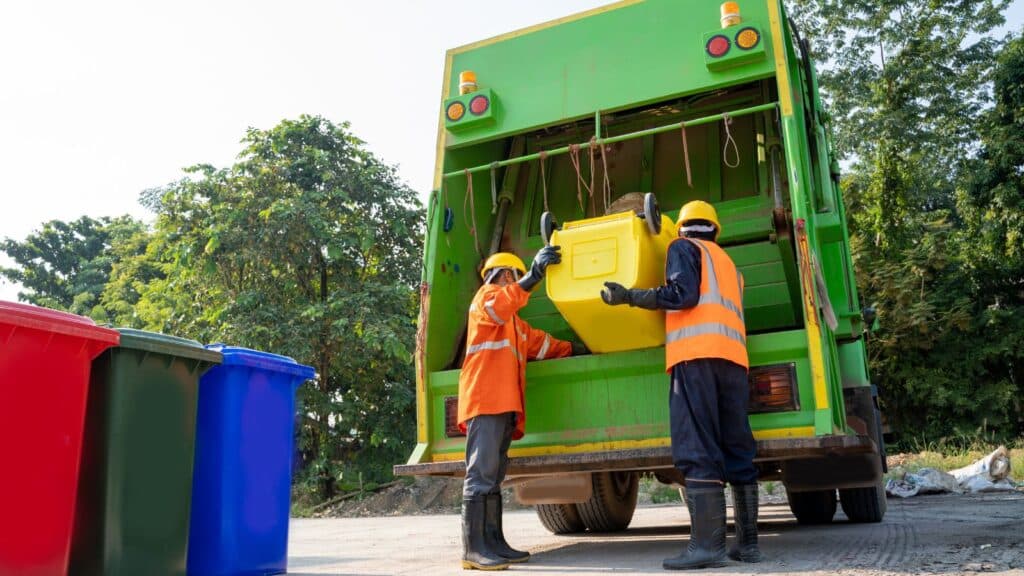 Sanitation workers dumping trash into a garbage truck