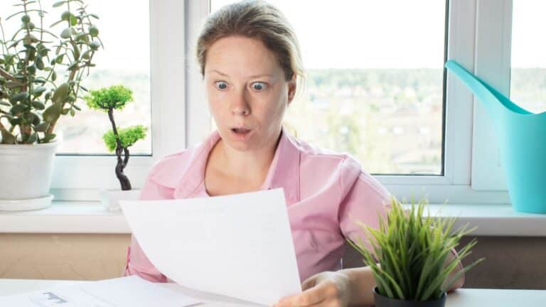 Woman looking at a paper with a look of shock on her face