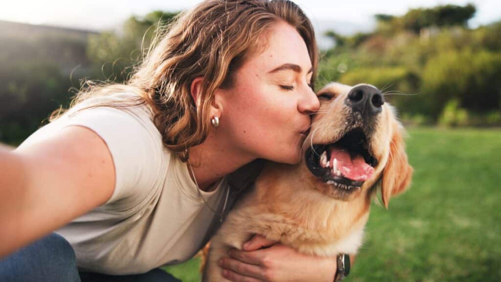 Woman kissing her dog in a field