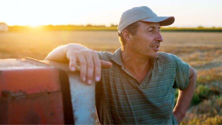 Famer in the field leaning on his tractor