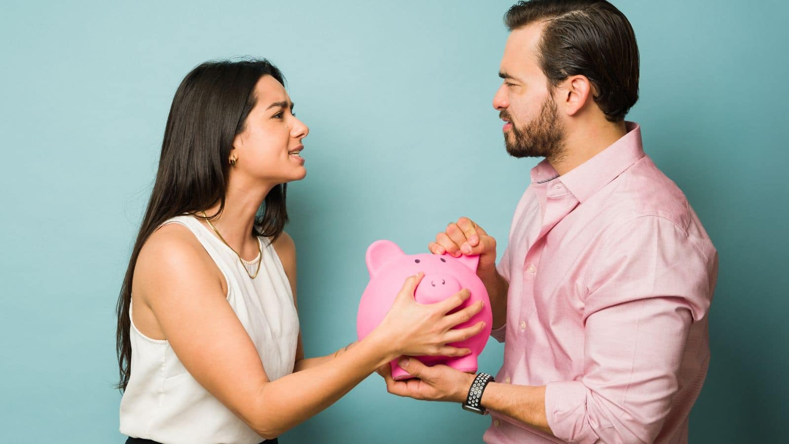 Couple fighting over a pink piggy bank