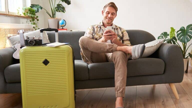 Man sitting on the couch with his suitcase waiting to leave for a trip