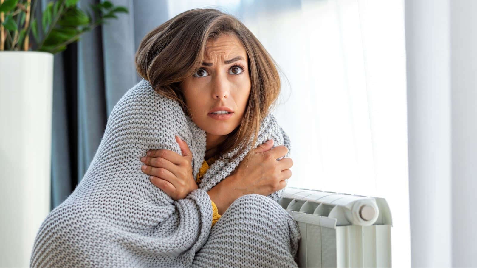 Young woman freezing and covered in a blanket