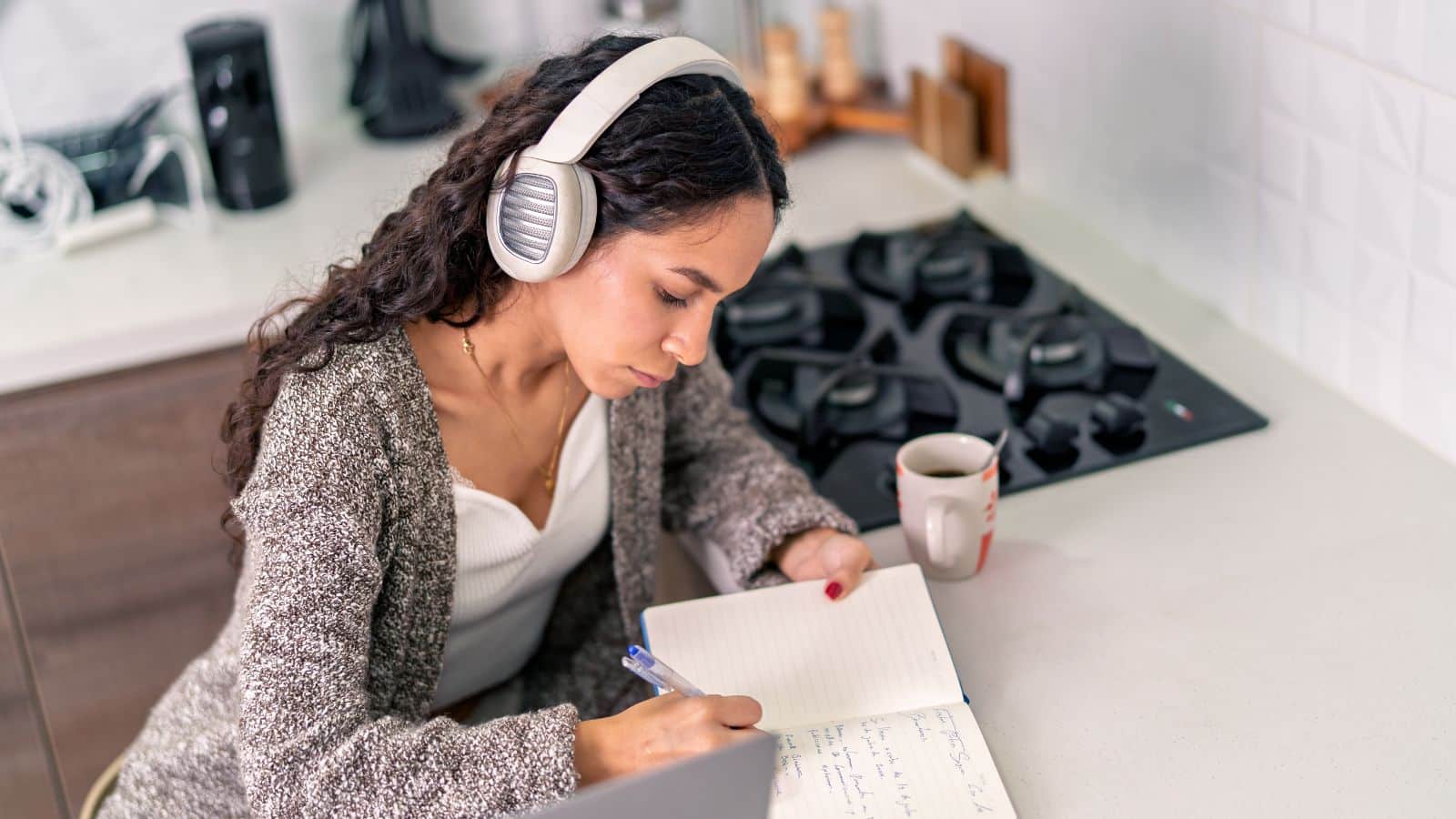 Woman wearing headphones writing in a notebook