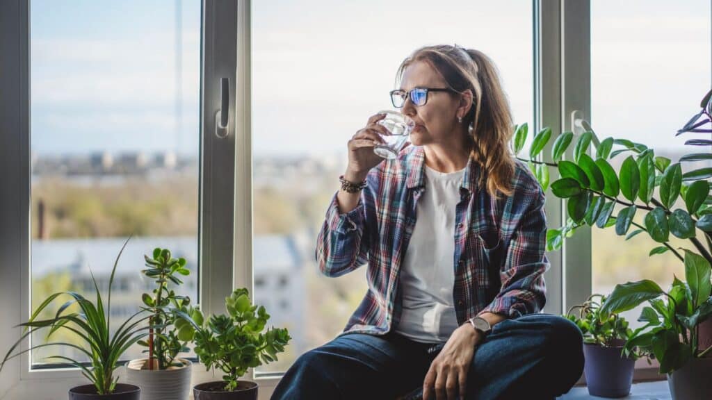 Woman sitting in front of windows drinking water