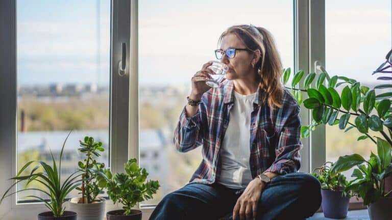 Woman sitting in front of windows drinking water