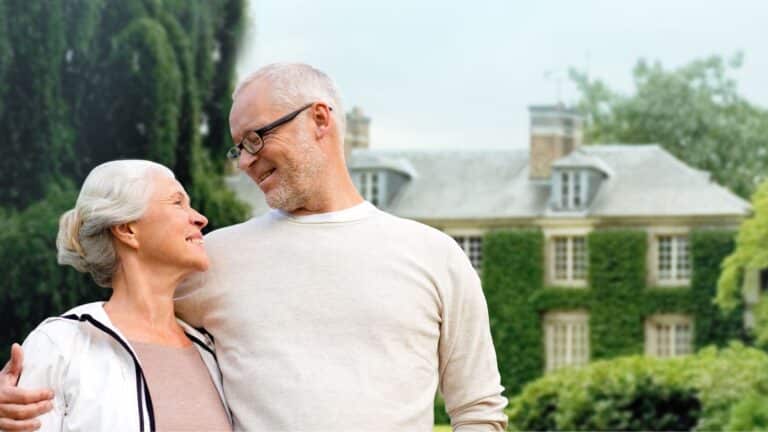 Older couple standing in front of their massive home