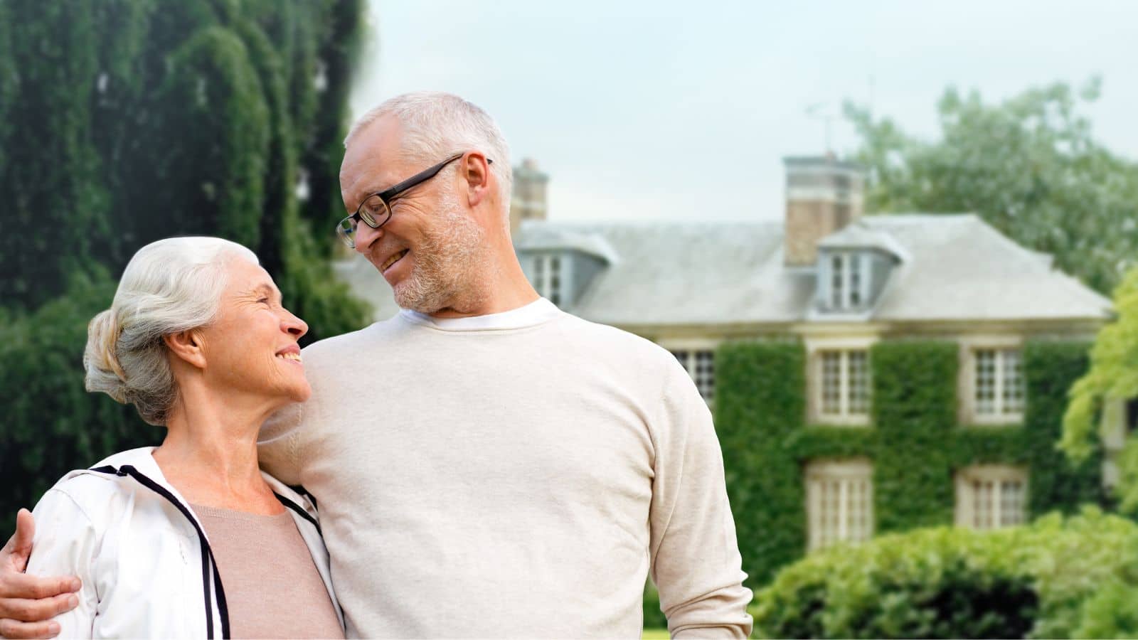 Older couple standing in front of their massive home