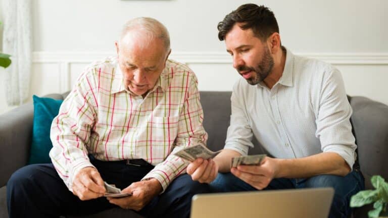 Adult man giving his elderly father money
