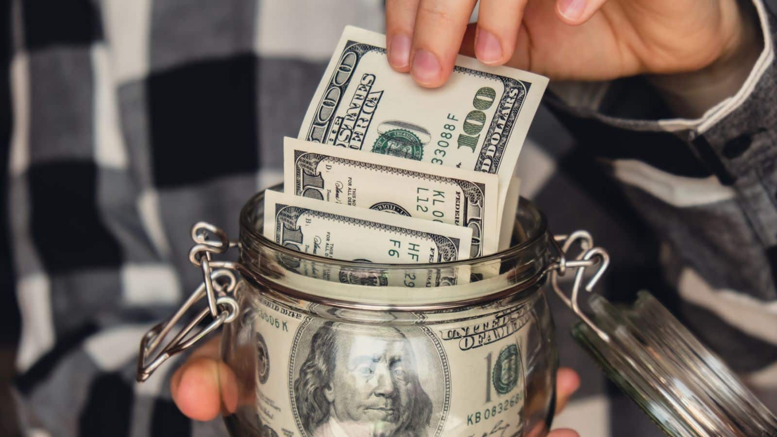 Person taking hundred dollar bills out of a jar