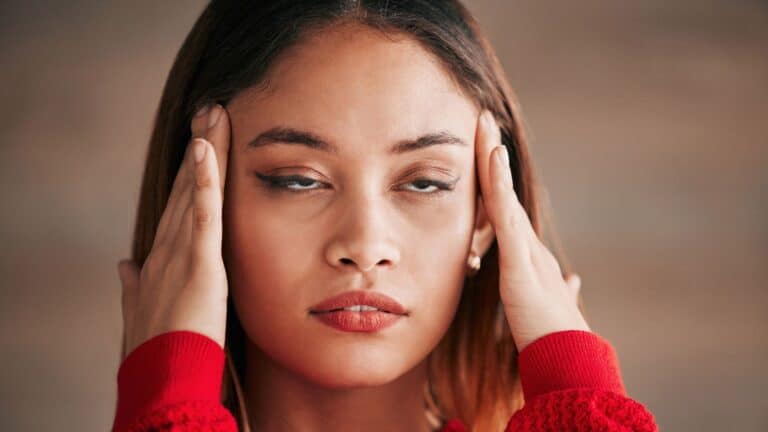 Woman holding her head like it hurts and looking annoyed