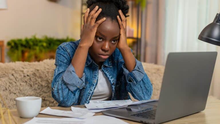 Woman sitting at her laptop paying bills and looking stressed