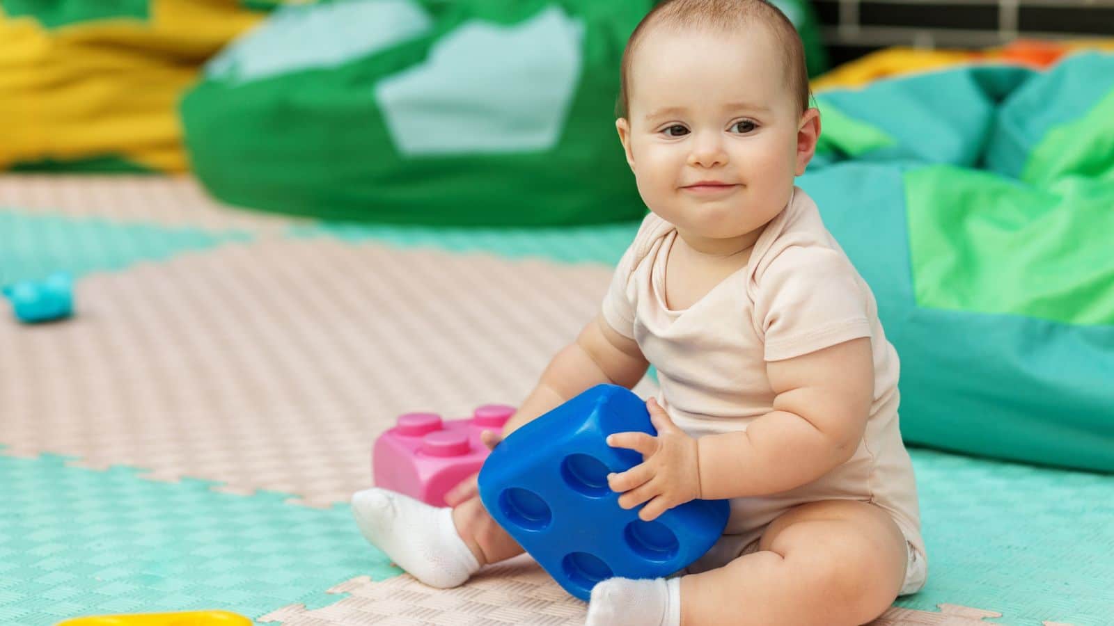 Baby sitting on the floor in daycare holding a toy