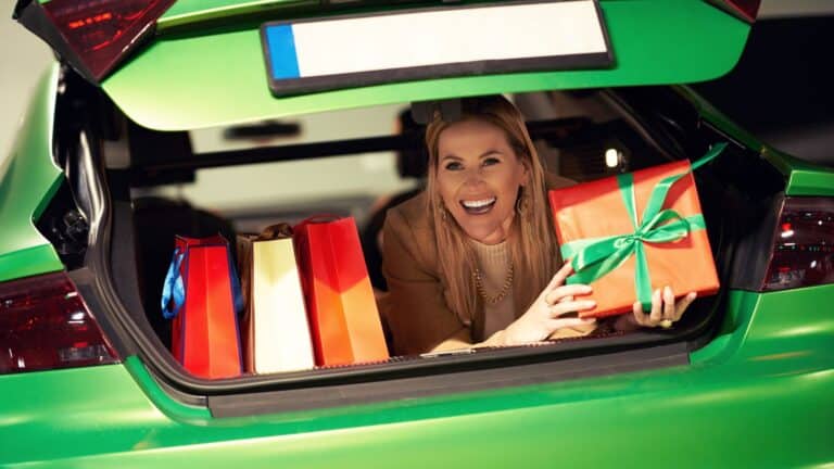 Woman hiding in trunk with a bunch of bags and packages