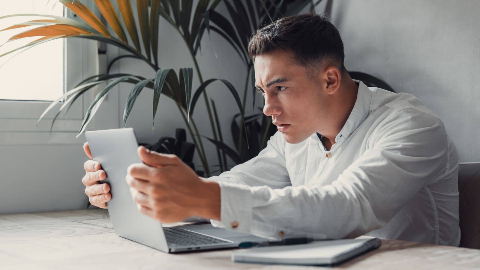 Young man holding his laptop and looking worried