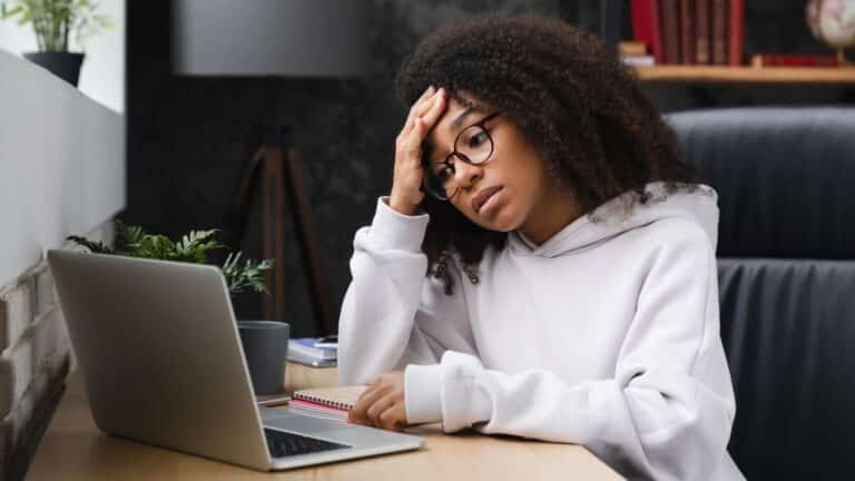 Young woman sitting at her computer looking very worried