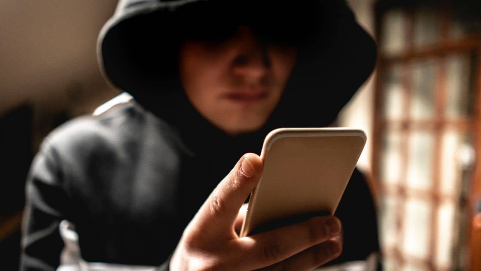 Kid looking at his phone looking shady in a hoodie