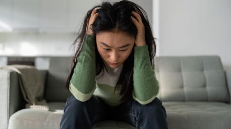 Woman sitting on couch with her head in her hands