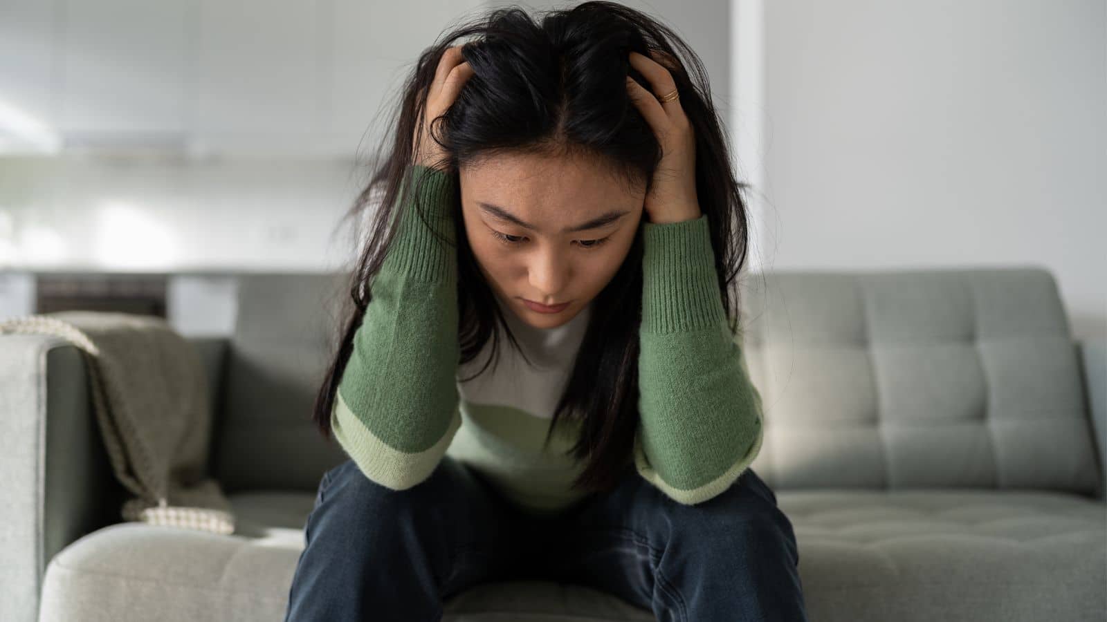 Woman sitting on couch with her head in her hands