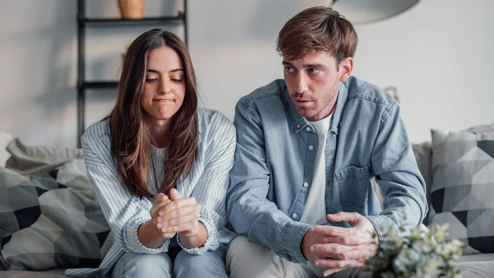 Couple sitting on the couch looking upset with each other