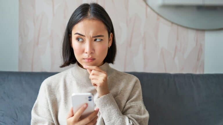 Young woman sitting on a couch looking at her phone