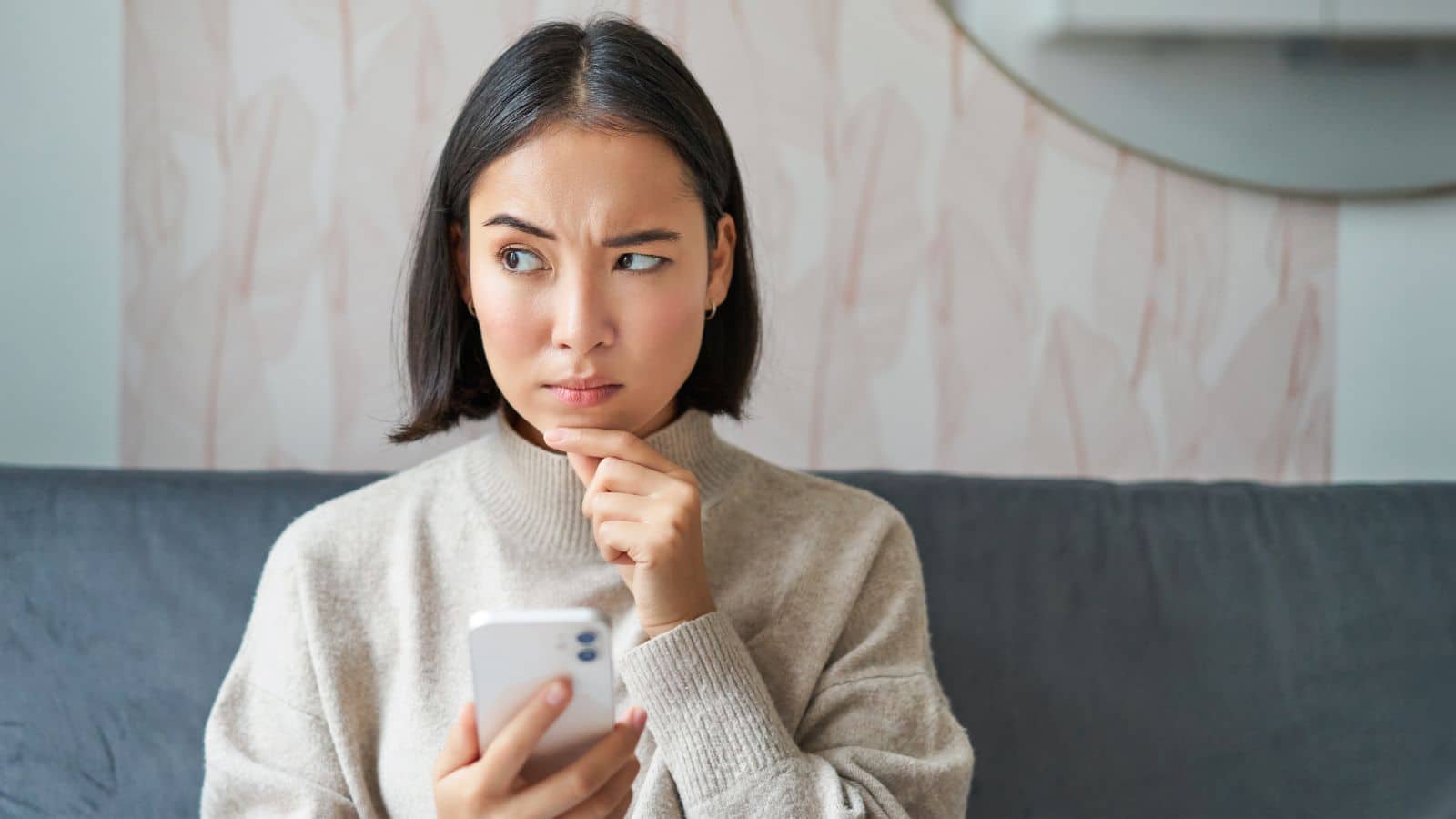 Young woman sitting on a couch looking at her phone