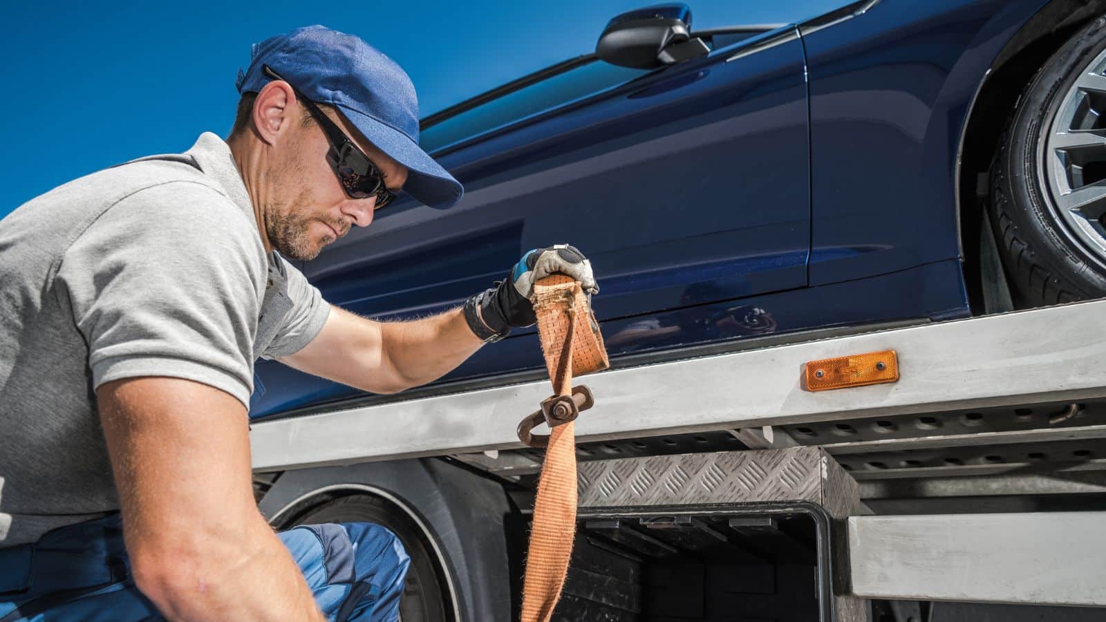 Man loading a car onto a flatbed truck