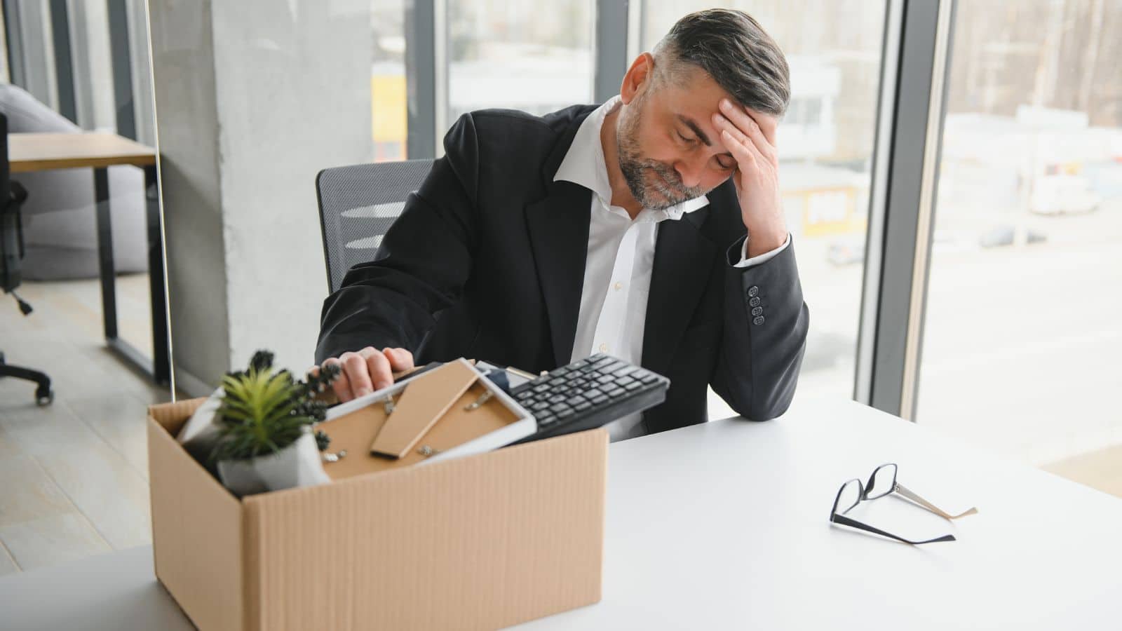 Man sitting at desk upset with his stuff in a box