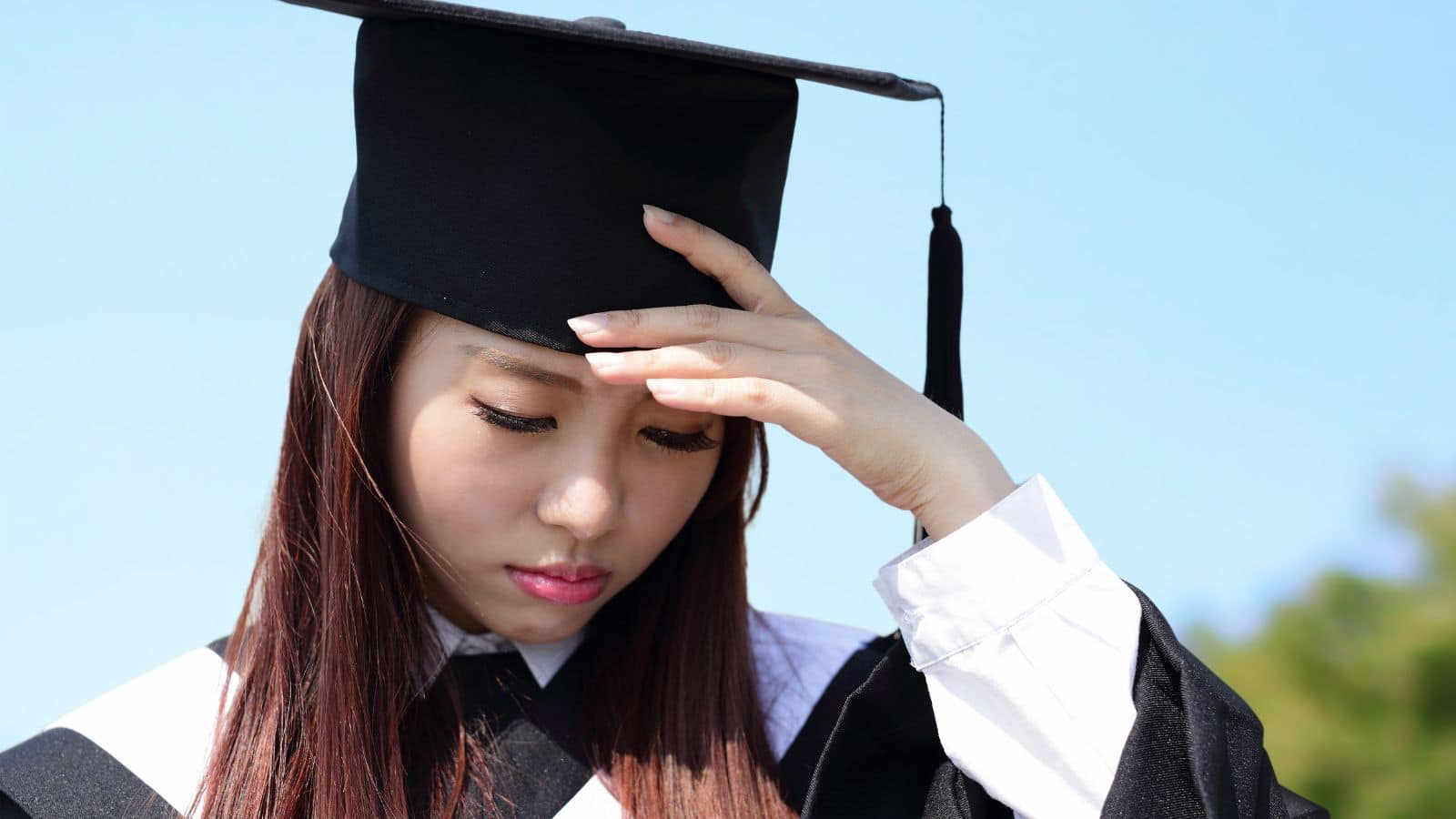 Female graduate looking sad in her cap and gown