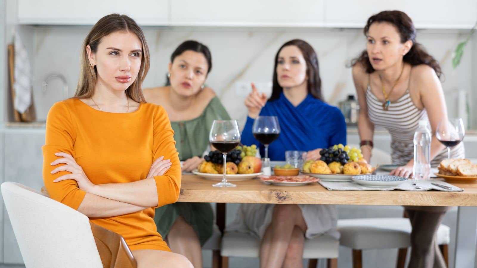 Four women sitting at a table looking angry with each other