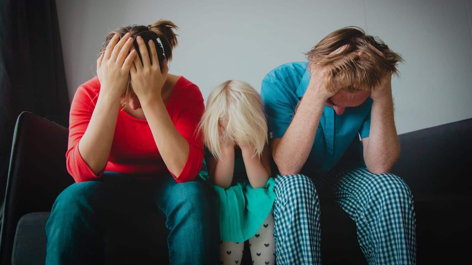 Parents sitting with child with their heads in their hands
