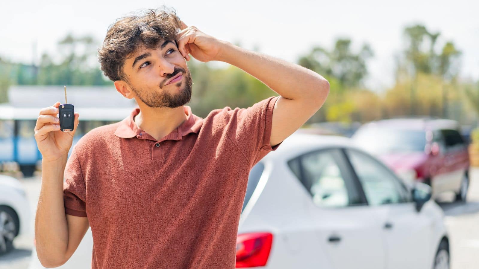 Man holding a car key with a confused look on his face
