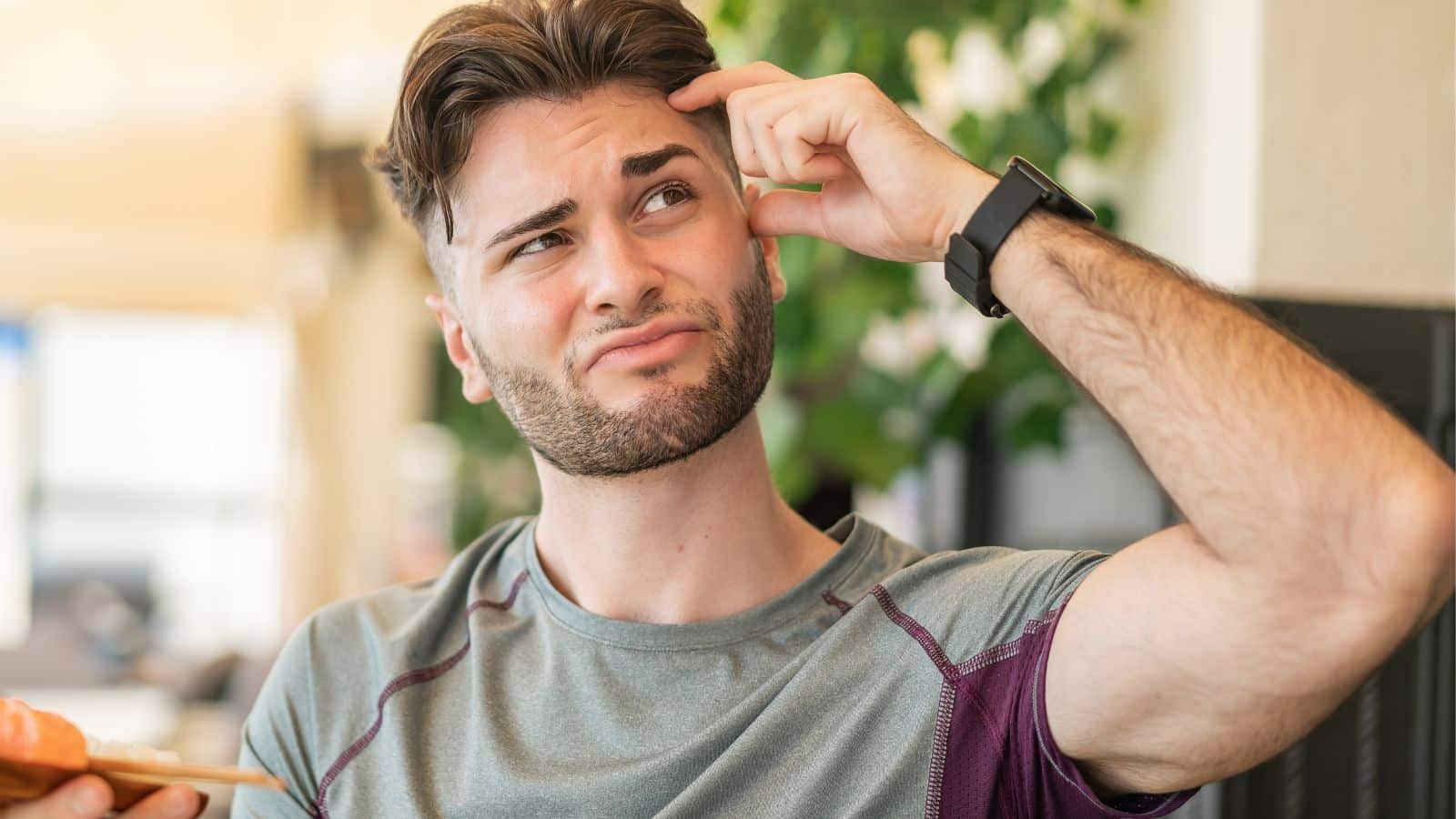 Man raising his eyebrow and scratching his head
