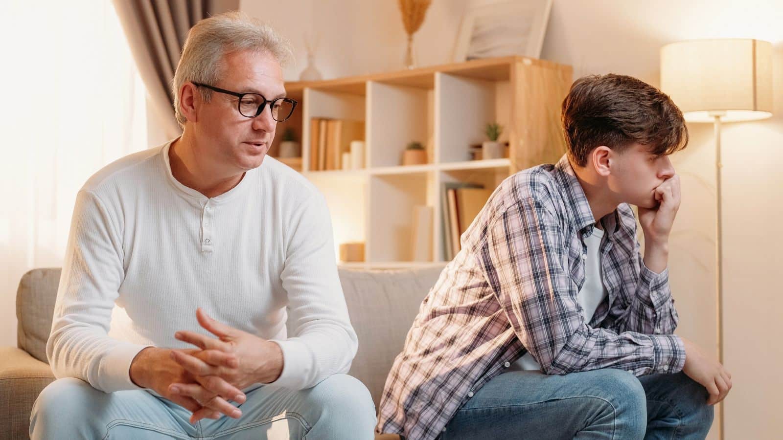 Father and teenage son sitting angry on the couch