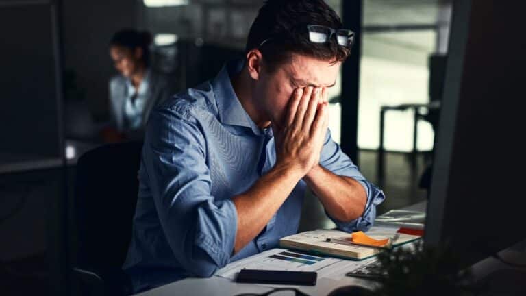 Man working at his computer looking stressed