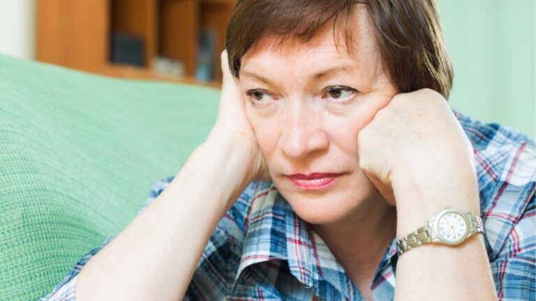 Woman sitting with her hands on her face looking worried