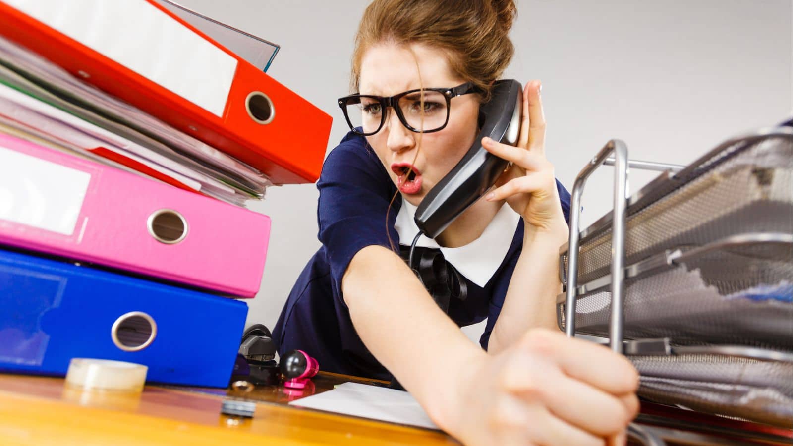 Secretary with a messy desk yelling on the phone