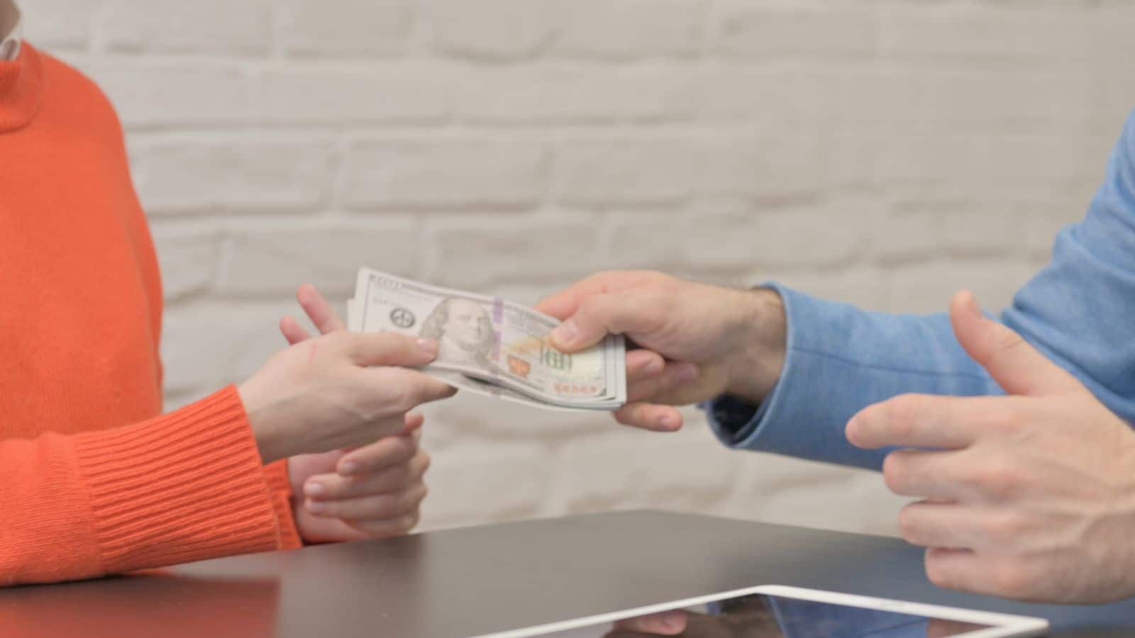 Person handing a bunch of cash to another