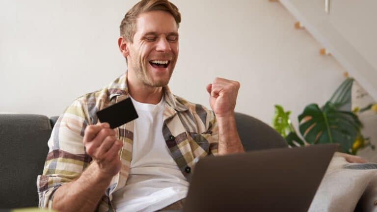 Man holding his credit card and looking happy
