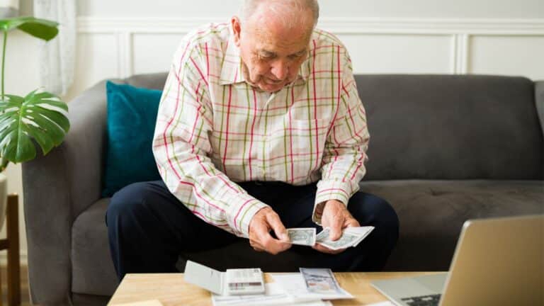 Old man counting money at a table