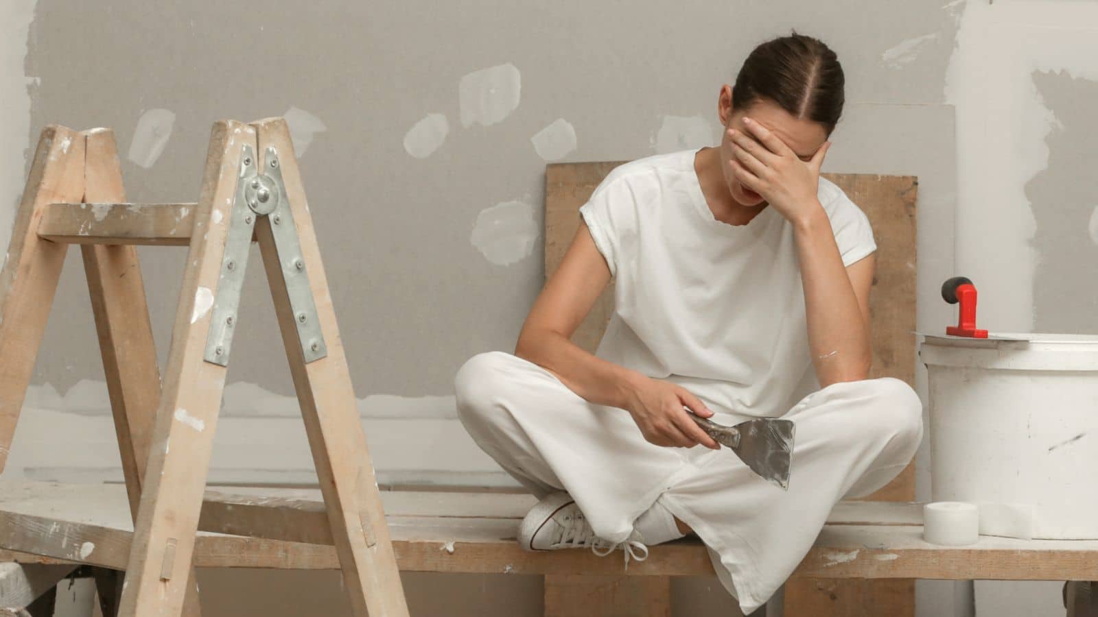 Woman sitting on table looking tired while working on house projects