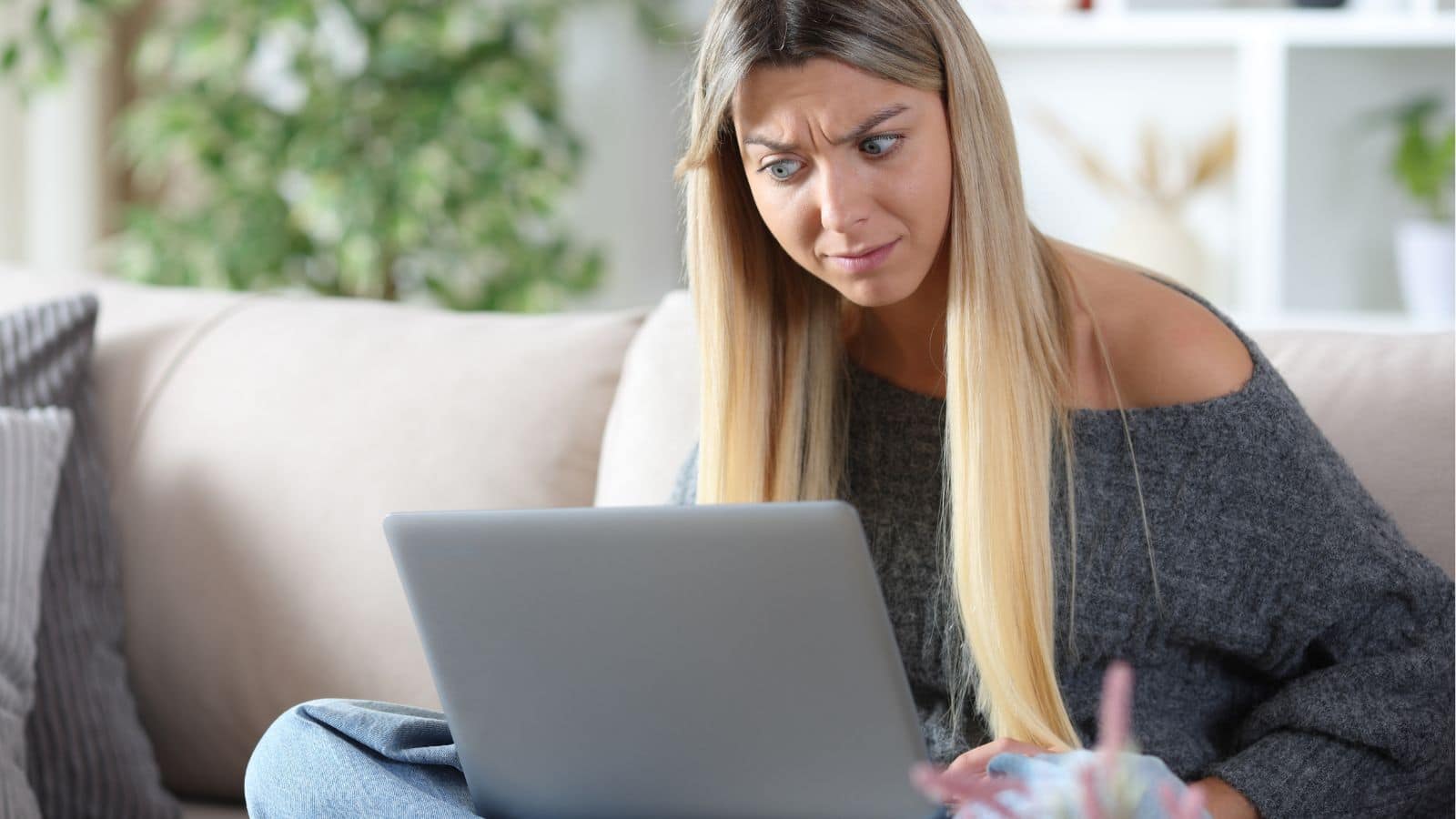 Young woman looking annoyed at her laptop