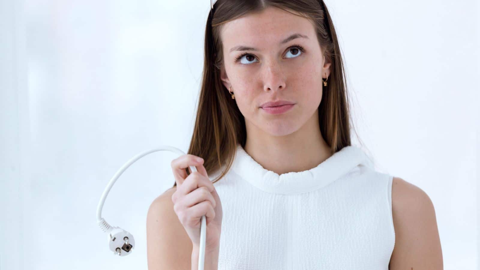 Young woman holding a cord looking annoyed