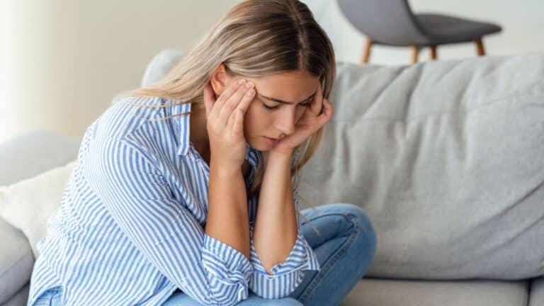 Woman looking very upset and in pain holding her head in her hands