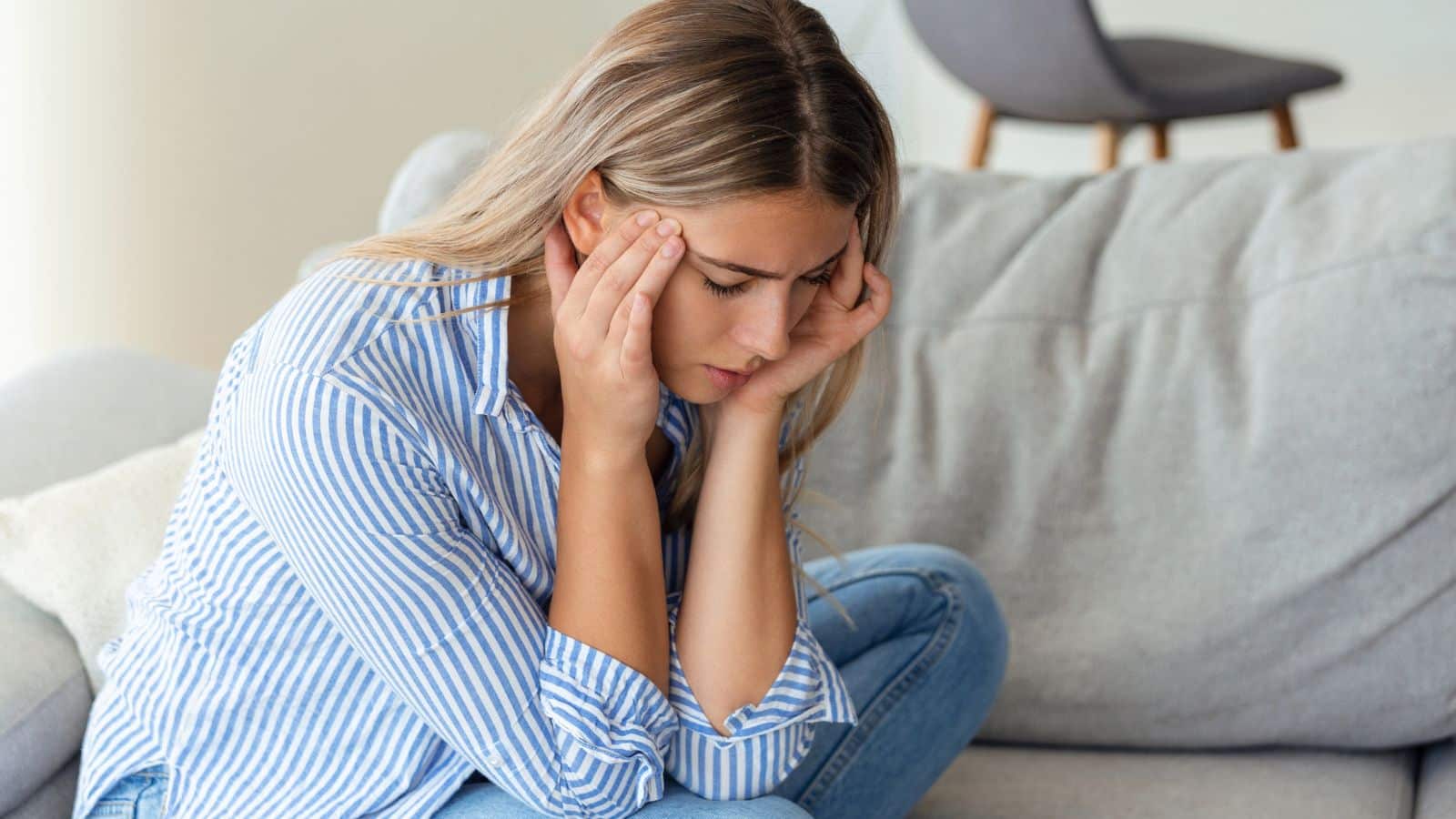 Woman looking very upset and in pain holding her head in her hands