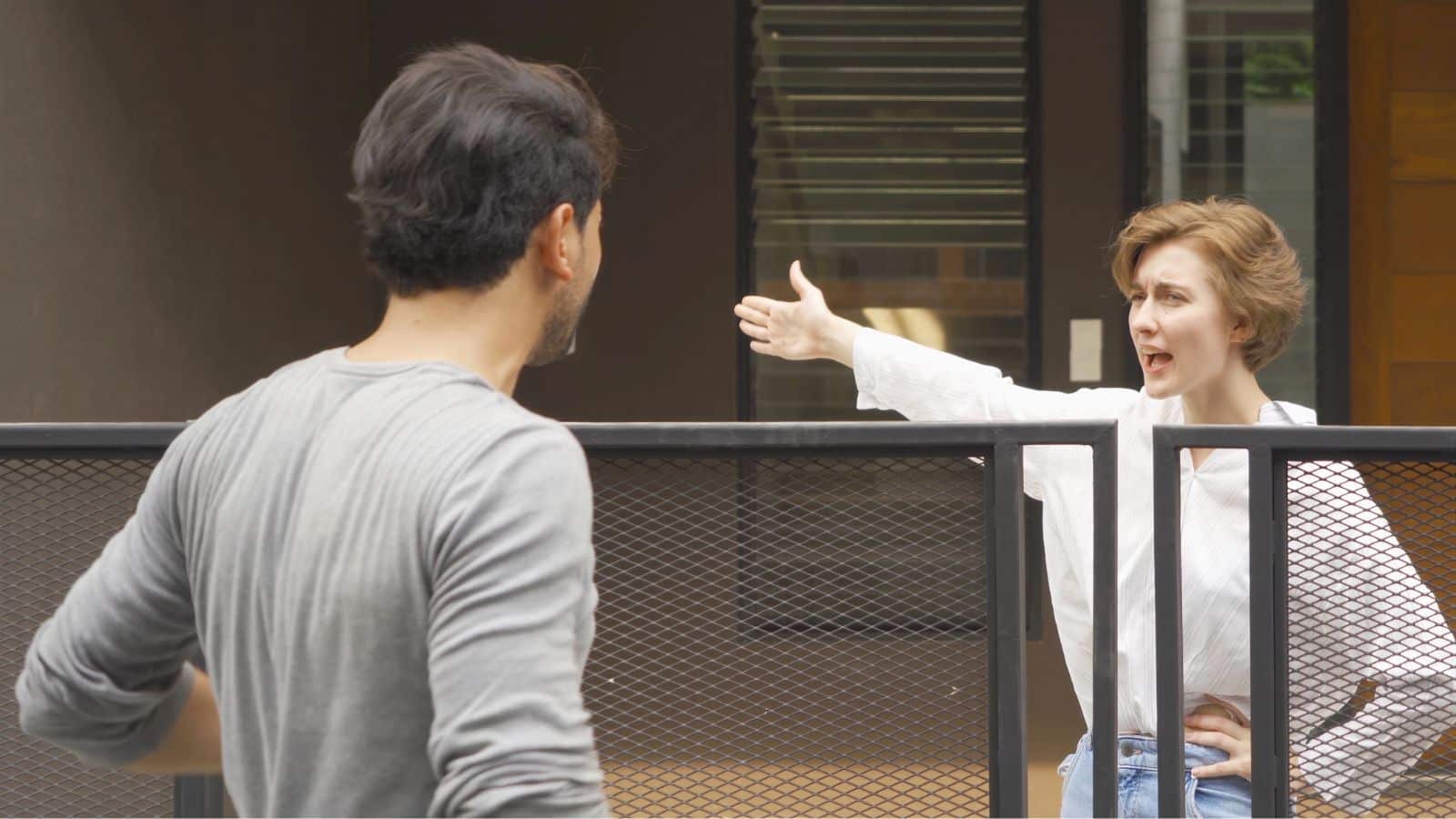 Female and male neighbors arguing across a fence