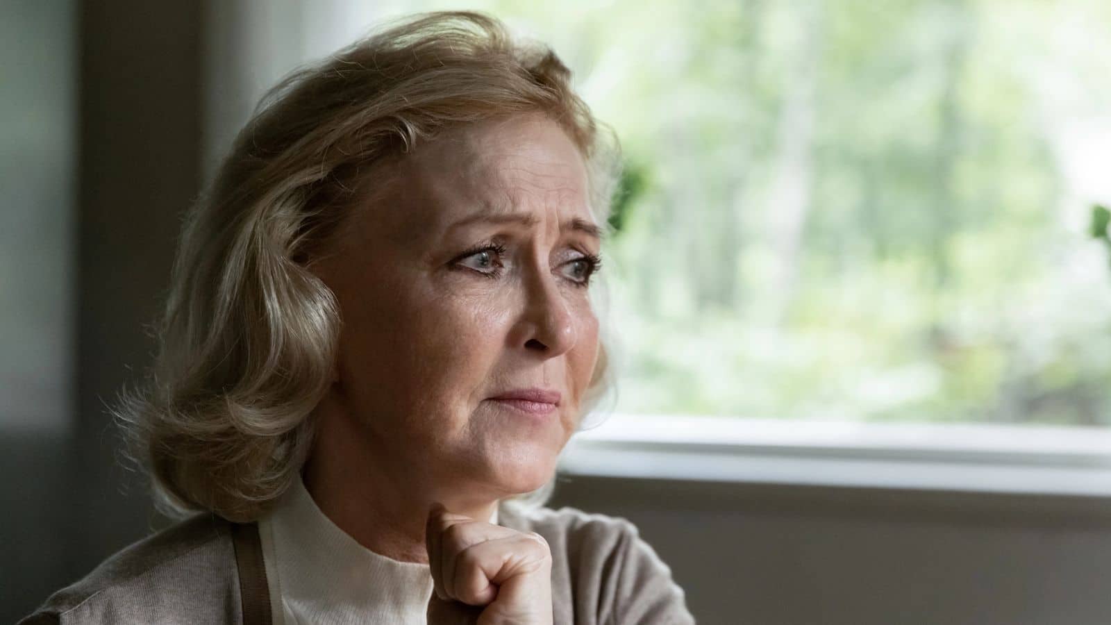 Sad older woman sitting next to a window